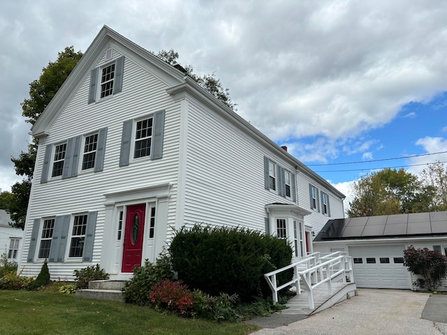 view of front facade with a front yard, a garage, and solar panels