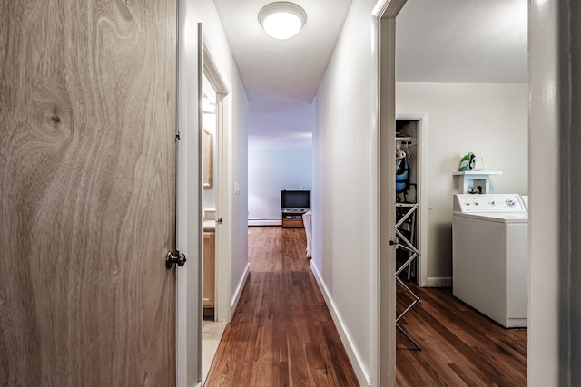 corridor featuring baseboard heating, dark hardwood / wood-style floors, and washer / dryer