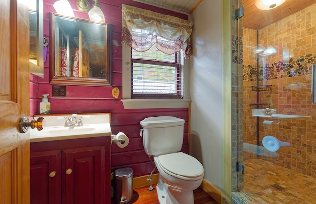 bathroom with tiled shower, hardwood / wood-style floors, vanity, and toilet