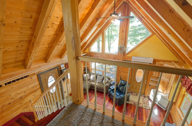 interior space featuring ceiling fan, wood ceiling, lofted ceiling with beams, hardwood / wood-style floors, and a wall unit AC