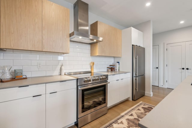 kitchen with light countertops, backsplash, modern cabinets, appliances with stainless steel finishes, and wall chimney exhaust hood