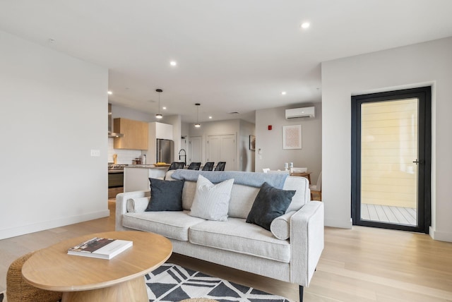 living area featuring baseboards, recessed lighting, a wall unit AC, and light wood-style floors