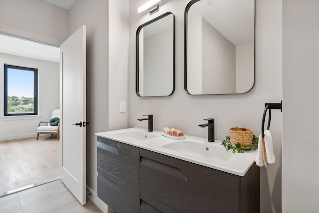 bathroom with baseboards, double vanity, and a sink