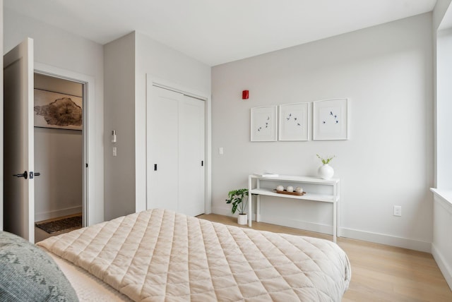 bedroom with baseboards, a closet, and light wood-style floors
