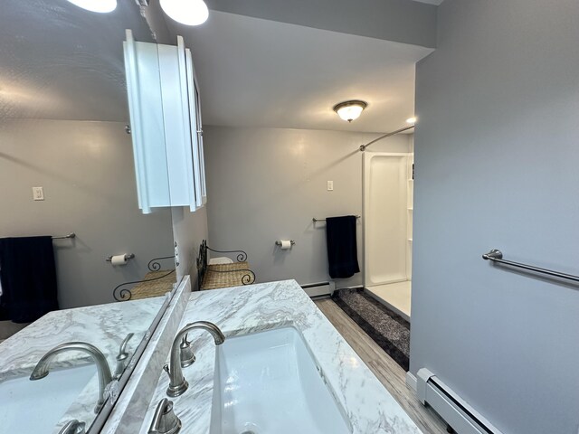 bathroom with hardwood / wood-style floors, baseboard heating, and vanity