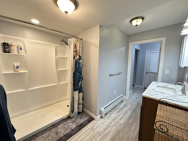 bathroom with wood-type flooring, vanity, a shower with shower curtain, and a baseboard radiator