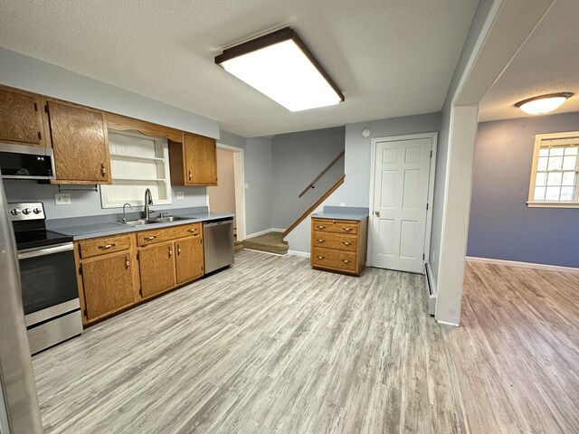 kitchen featuring appliances with stainless steel finishes, a textured ceiling, sink, and light hardwood / wood-style flooring