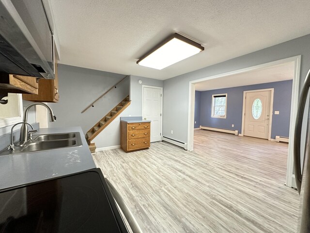 kitchen with a textured ceiling, baseboard heating, light hardwood / wood-style flooring, and sink