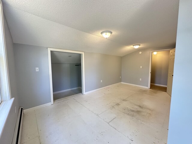 empty room featuring a textured ceiling, lofted ceiling, and baseboard heating