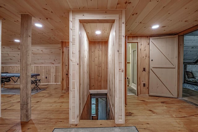 corridor featuring wood walls, light hardwood / wood-style floors, and wooden ceiling