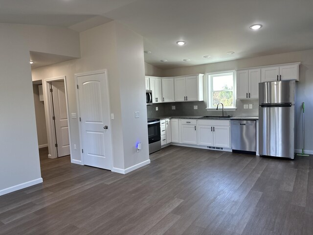 kitchen featuring sink, tasteful backsplash, white cabinetry, appliances with stainless steel finishes, and dark hardwood / wood-style flooring