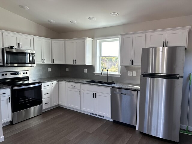 kitchen with stainless steel appliances, vaulted ceiling, dark hardwood / wood-style floors, and white cabinetry