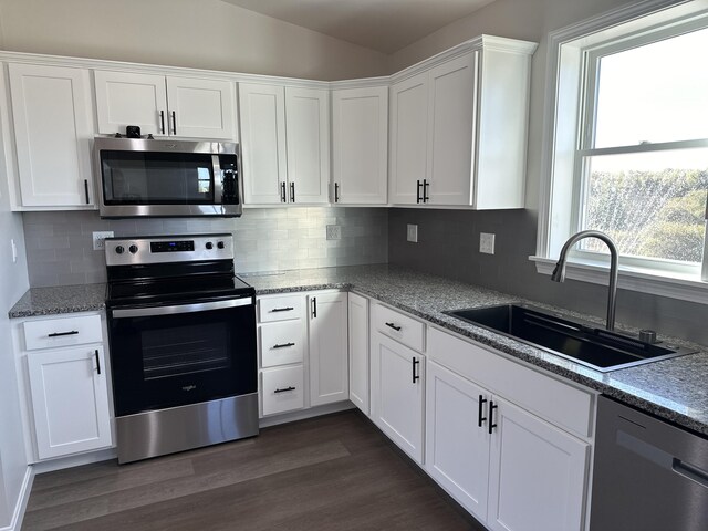 kitchen featuring appliances with stainless steel finishes, tasteful backsplash, white cabinets, dark hardwood / wood-style floors, and sink