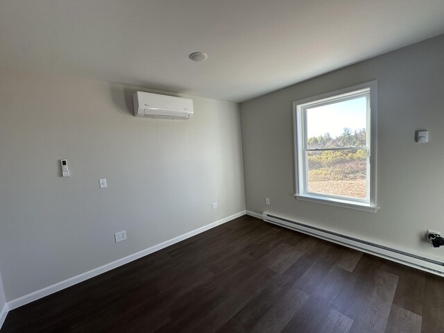 spare room with a baseboard radiator, a wall unit AC, and dark hardwood / wood-style floors