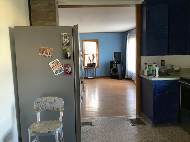 kitchen with blue cabinetry, stainless steel fridge, light wood-type flooring, and electric range