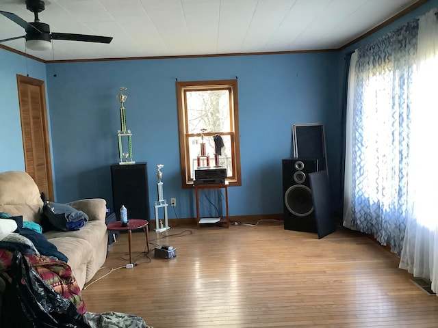 living area featuring light hardwood / wood-style flooring, ceiling fan, and crown molding