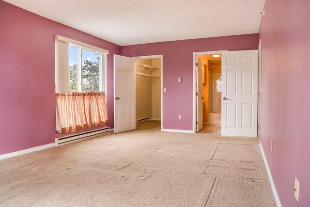 215 E Grand Ave Unit 206, Old Orchard Beach, ME 04064 - unfurnished bedroom with a baseboard heating unit, light colored carpet, a spacious closet, baseboards, and a textured ceiling