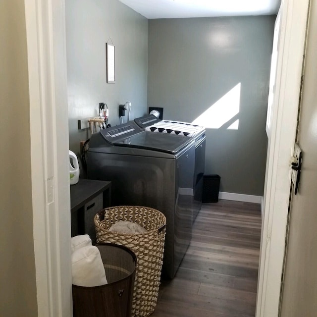 clothes washing area with dark wood-type flooring and independent washer and dryer