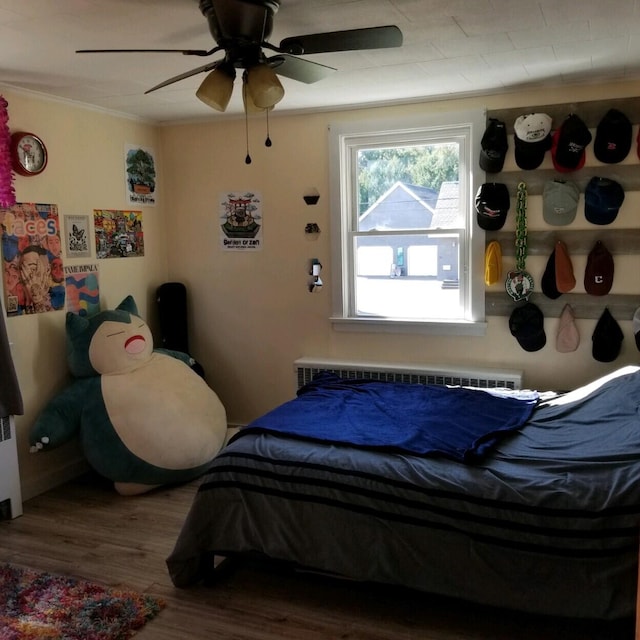 bedroom with ceiling fan, radiator, crown molding, and hardwood / wood-style floors