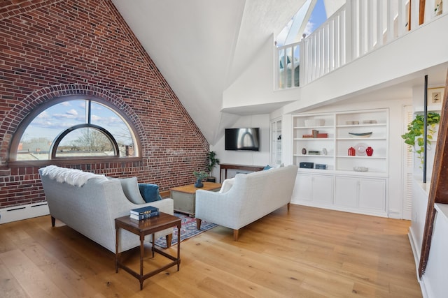 living area featuring a baseboard radiator, high vaulted ceiling, brick wall, and light wood-type flooring