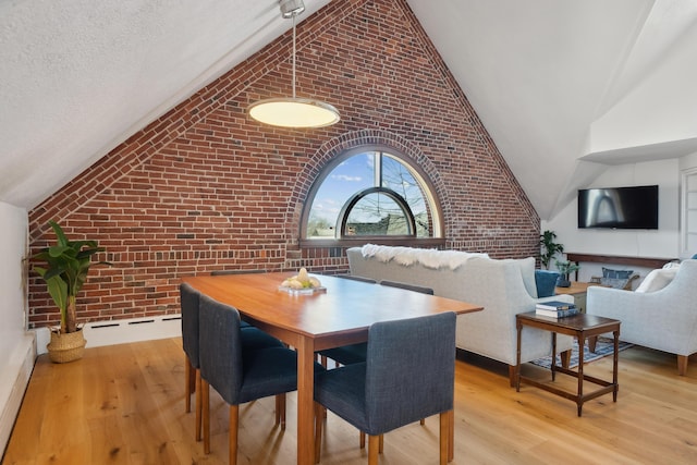 dining room with high vaulted ceiling, wood finished floors, brick wall, and a textured ceiling