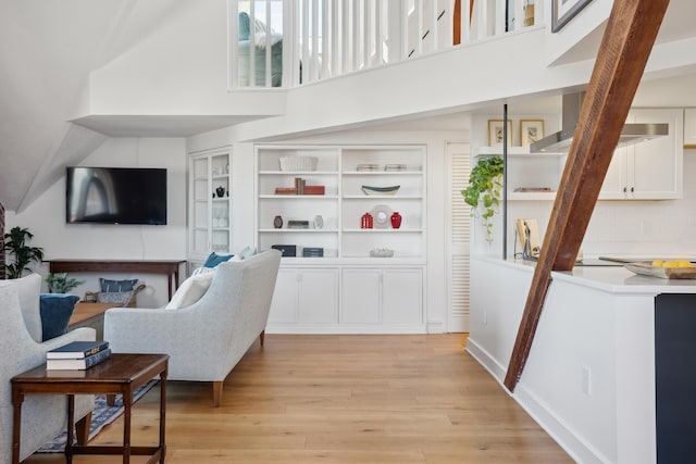 living area featuring a towering ceiling and light wood finished floors