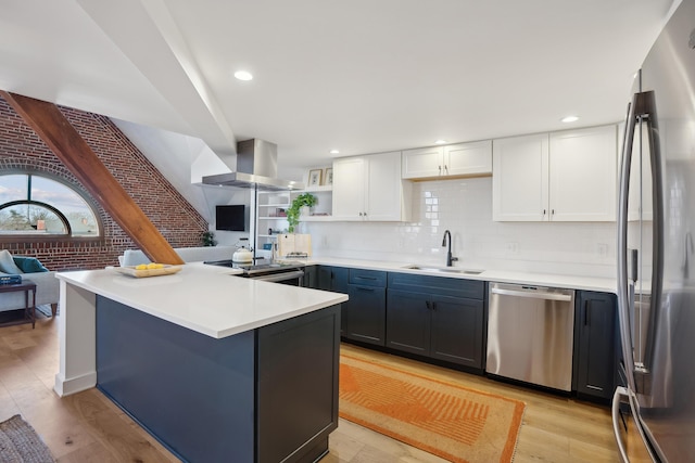 kitchen with white cabinets, stainless steel appliances, a sink, island range hood, and light wood-style floors