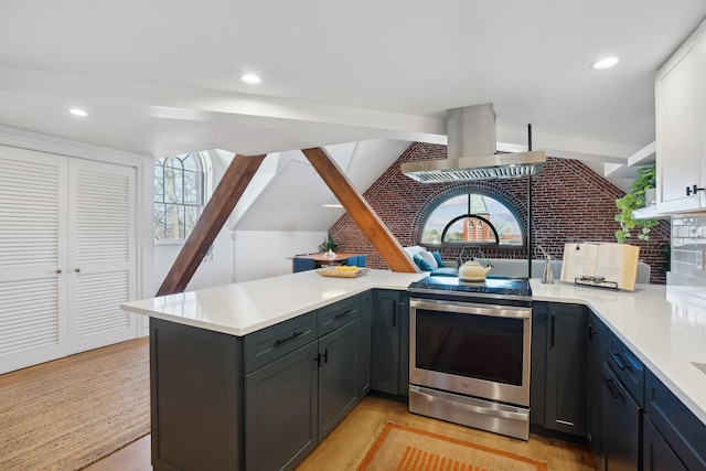 kitchen featuring light countertops, island exhaust hood, electric range, light wood-style floors, and a peninsula