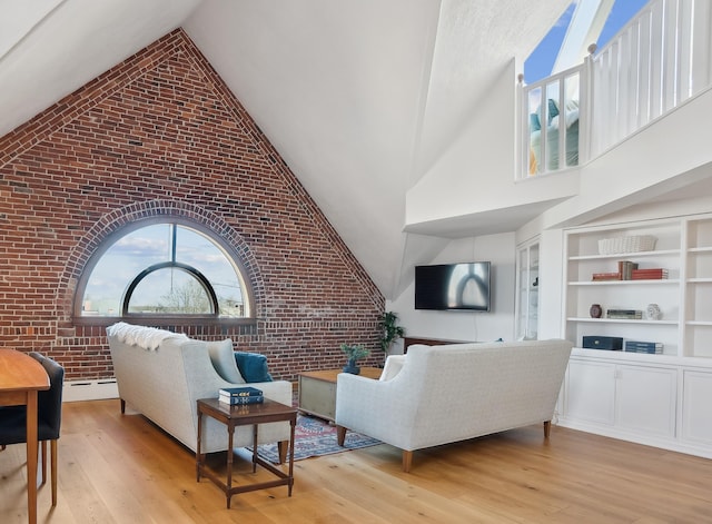 living room featuring high vaulted ceiling, built in shelves, brick wall, and light wood finished floors