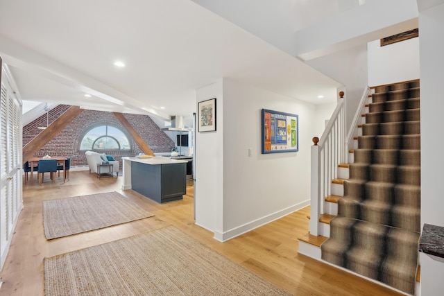 interior space with baseboards, stairs, recessed lighting, light wood-type flooring, and brick wall
