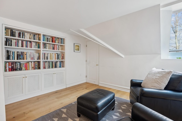 sitting room with built in features, lofted ceiling, wood finished floors, and plenty of natural light