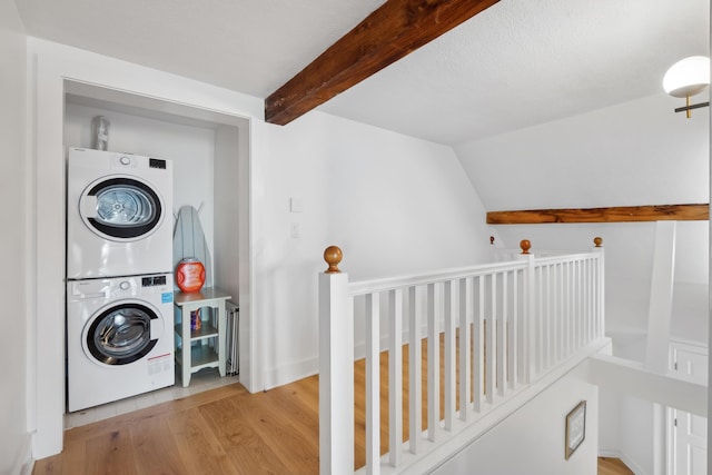 clothes washing area with stacked washing maching and dryer, laundry area, and wood finished floors
