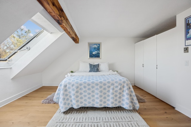 bedroom with light wood-style flooring, baseboards, and vaulted ceiling with skylight