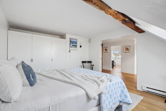 bedroom featuring a baseboard radiator, a closet, wood finished floors, and beam ceiling