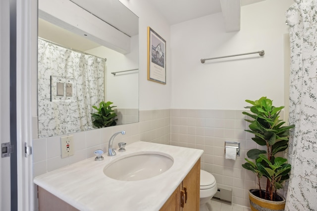 bathroom with a shower with curtain, vanity, tile walls, toilet, and a wainscoted wall