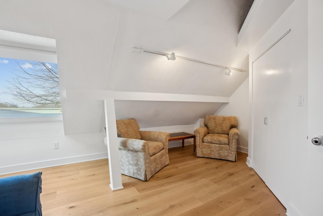living area with baseboards, lofted ceiling, and wood finished floors