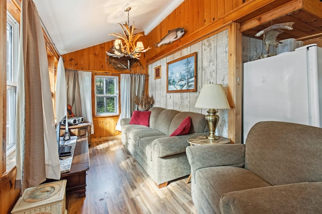 living room with lofted ceiling, ornamental molding, wooden walls, light hardwood / wood-style flooring, and a notable chandelier