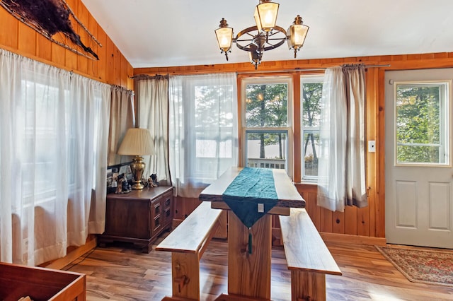 dining room featuring an inviting chandelier, wood walls, vaulted ceiling, and hardwood / wood-style floors