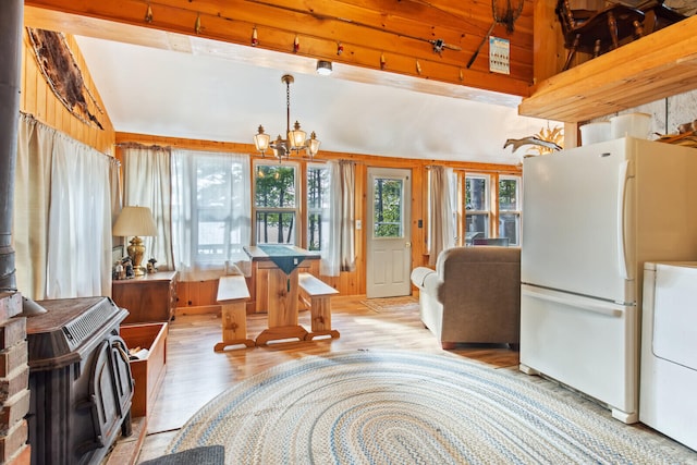 dining room featuring wood walls, a wood stove, washer / clothes dryer, an inviting chandelier, and light wood-type flooring