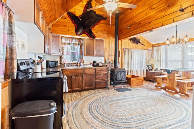 kitchen featuring light hardwood / wood-style flooring, a wood stove, wood walls, and stainless steel electric stove