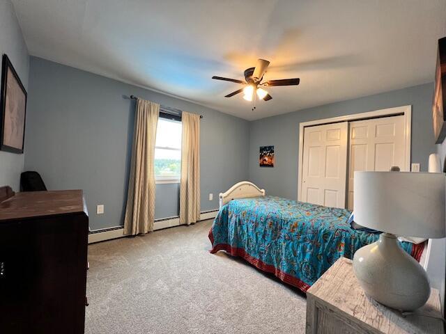 carpeted bedroom featuring ceiling fan, a baseboard radiator, and a closet