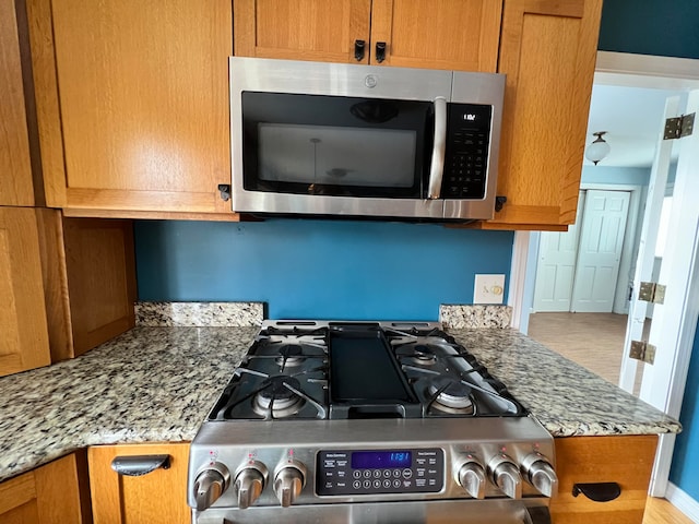 kitchen featuring appliances with stainless steel finishes and light stone counters