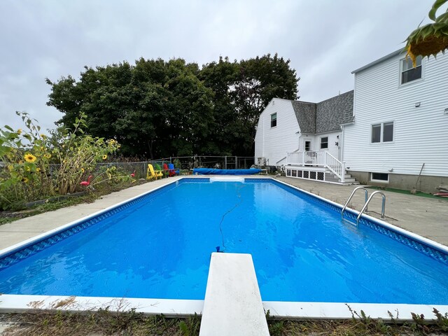 view of swimming pool with a diving board