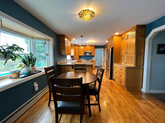 dining area with light wood-type flooring, baseboard heating, and sink