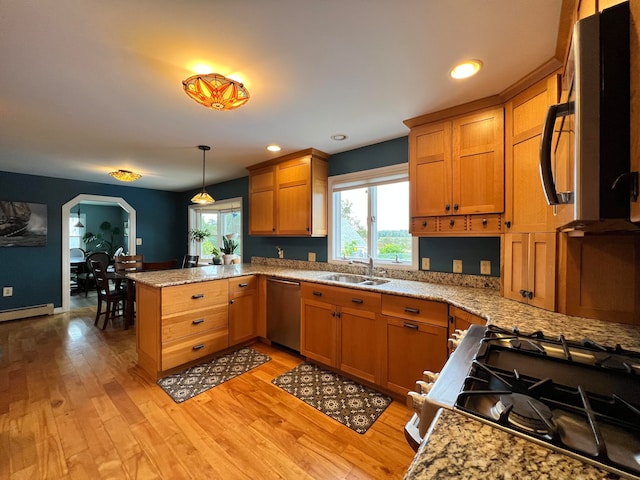 kitchen with light hardwood / wood-style floors, kitchen peninsula, stainless steel appliances, decorative light fixtures, and sink