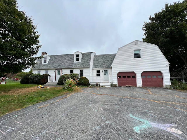 cape cod home with a front yard and a garage