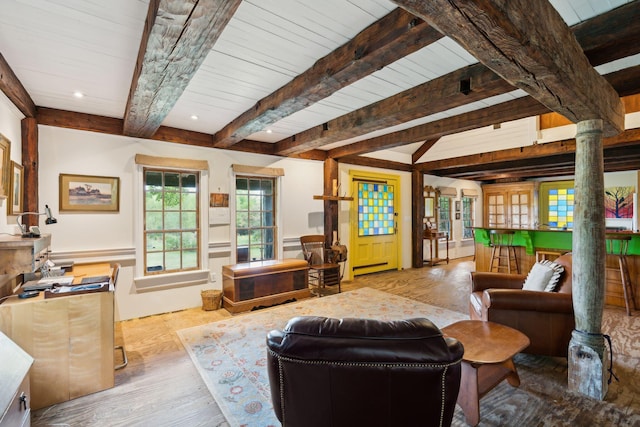 living room featuring decorative columns, light hardwood / wood-style floors, and beam ceiling