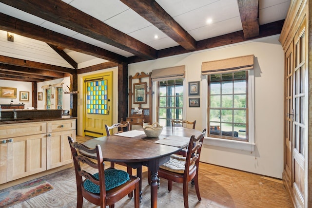 dining room featuring sink, light hardwood / wood-style flooring, and beam ceiling