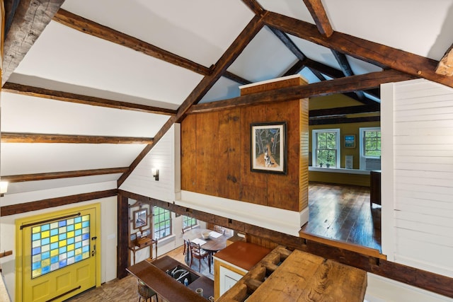 unfurnished living room featuring wood-type flooring, beamed ceiling, wooden walls, and high vaulted ceiling