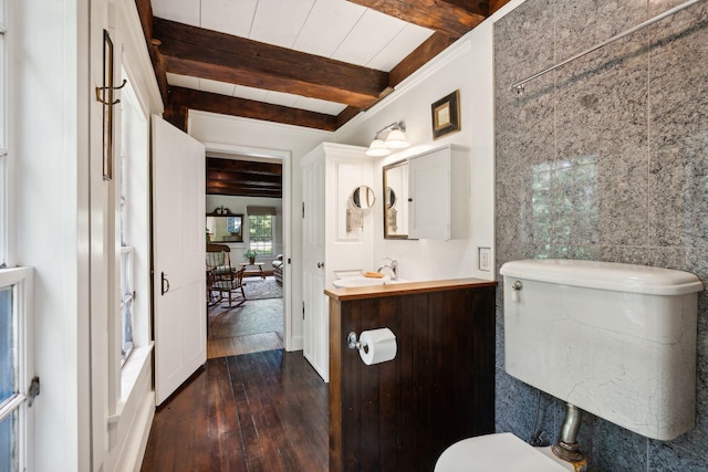 bathroom featuring hardwood / wood-style flooring, beam ceiling, walk in shower, vanity, and toilet